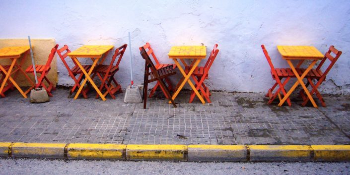 Stühle in den spanischen Nationalfarben in rot und gelb vor einer Tapas Bar in Conil, Spanien